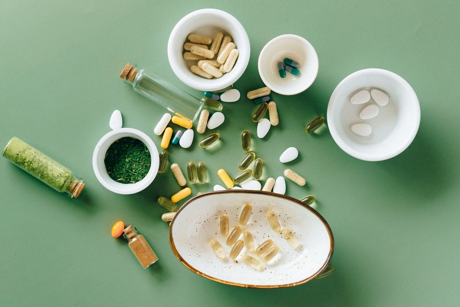 Een fles spermidine capsules op een tafel met groene bladeren op de achtergrond, symboliserend gezondheid en verjonging.