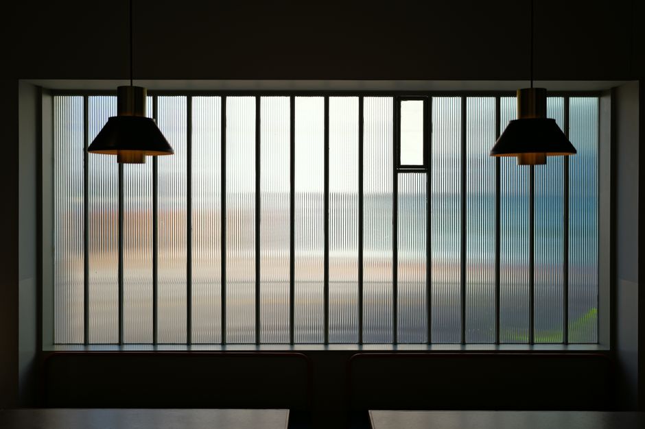 Minimalistische strakke hanglampen boven een moderne eettafel in een lichte woonkamer.